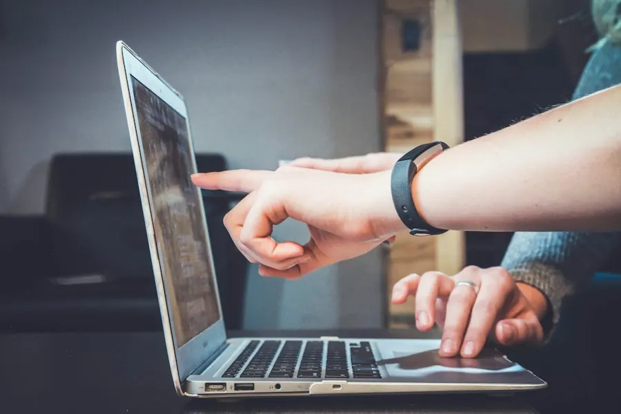 Dos personas colaboran frente a un portátil; una señala la pantalla mientras la otra usa el teclado, en una sesión de acompañamiento digital.